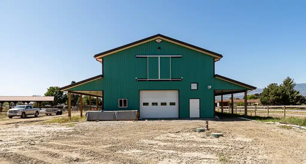 A turquoise post-frame equestrian barn