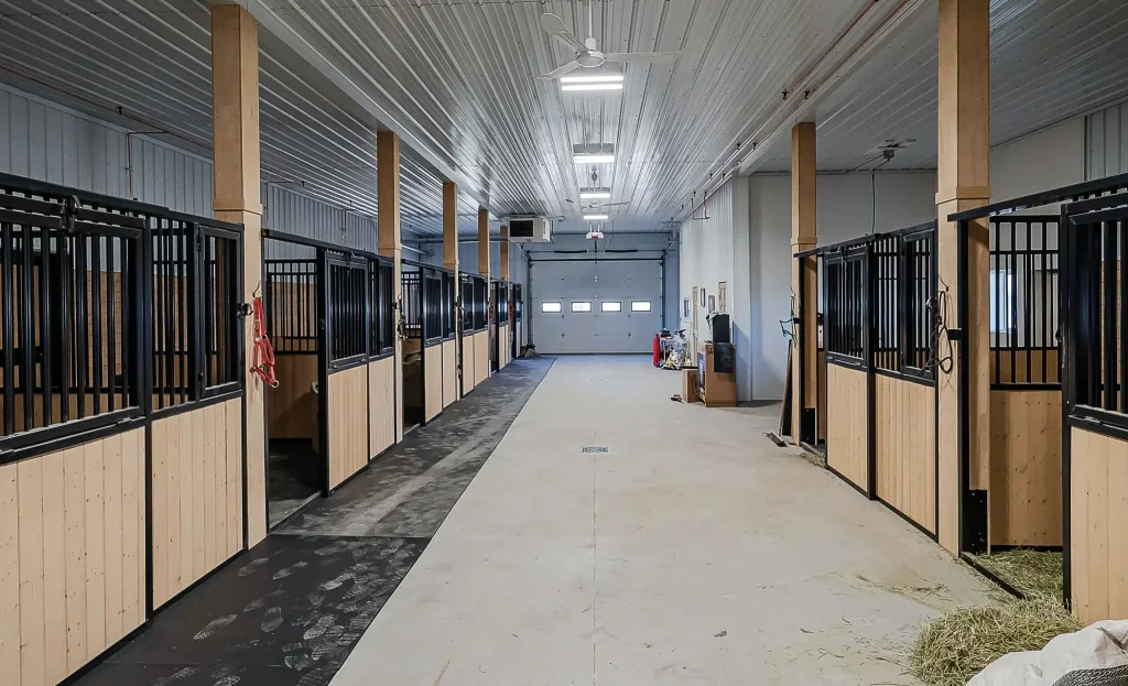 A turquoise post-frame equestrian barn