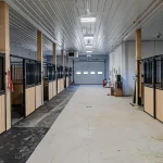 A turquoise post-frame equestrian barn