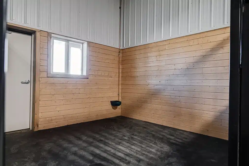 A turquoise post-frame equestrian barn