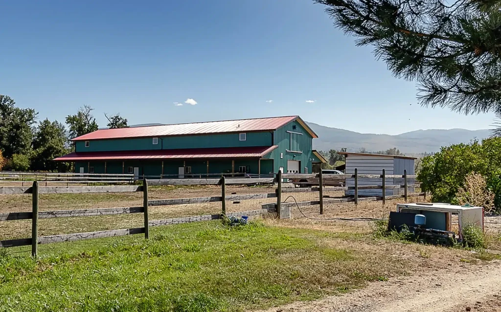 A turquoise post-frame equestrian barn
