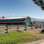A turquoise post-frame equestrian barn