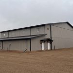 A hickory post-frame airplane hangar with 5 overhead doors and a bi-fold door
