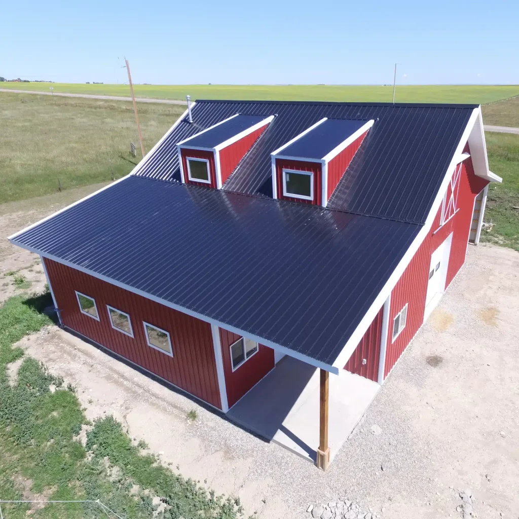 A bright red equestrian post-frame barn with an overhead door