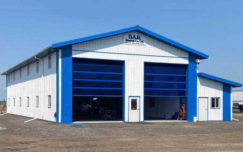 A bright white post-frame commercial building with two overhead doors