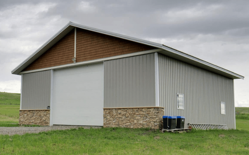 A stone grey lifestyle & Hobby shop with wainscotting, soffits, and one overhead door