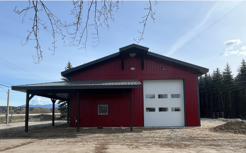 A Dark Red lifestyle & Hobby post-frame shop with one overhead door, soffits and timber accents