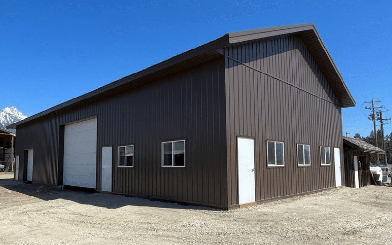 A coffee brown agricultural post-frame shop with two overhead doors