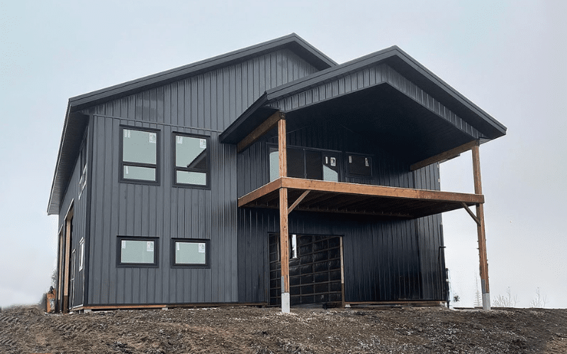 a black lifestyle & hobby post-frame shop with three overhead doors