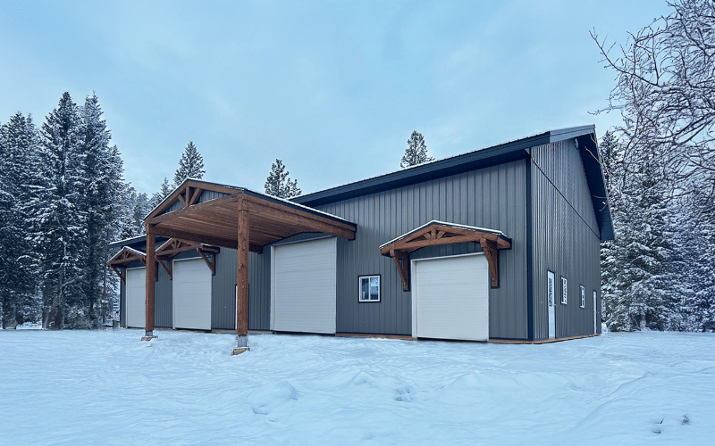 A sable agricultural post-frame shop with three overhead doors and timber accents
