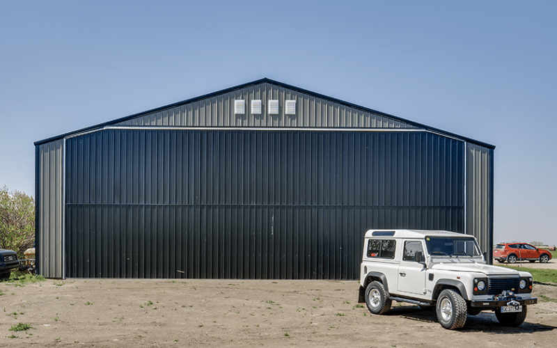 A sable post-frame airplane hangar with a bi-fold door