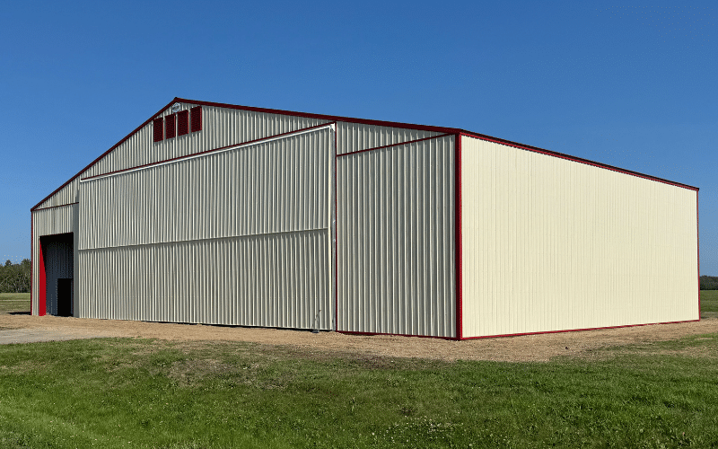 An antique linen post-frame airplane hangar with an overhead and bi-fold door