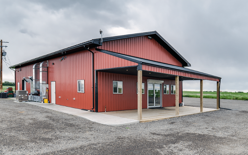 A tile red post-frame commercial build with one overhead door and soffits