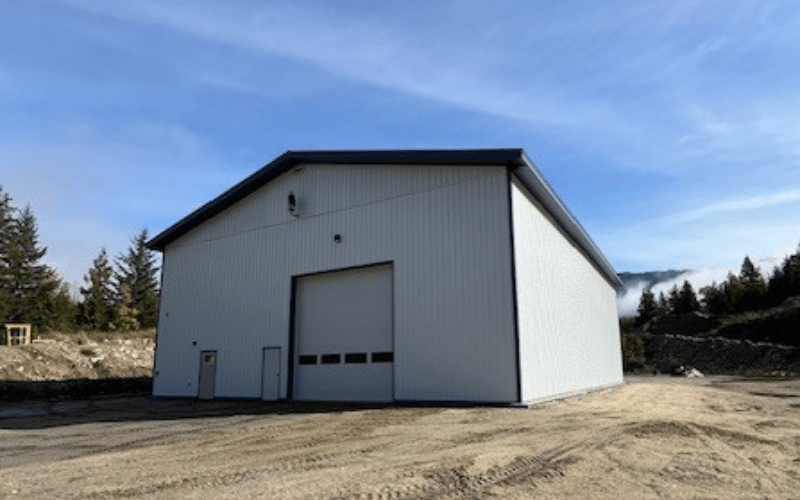A bright white post-frame commercial build with two overhead doors