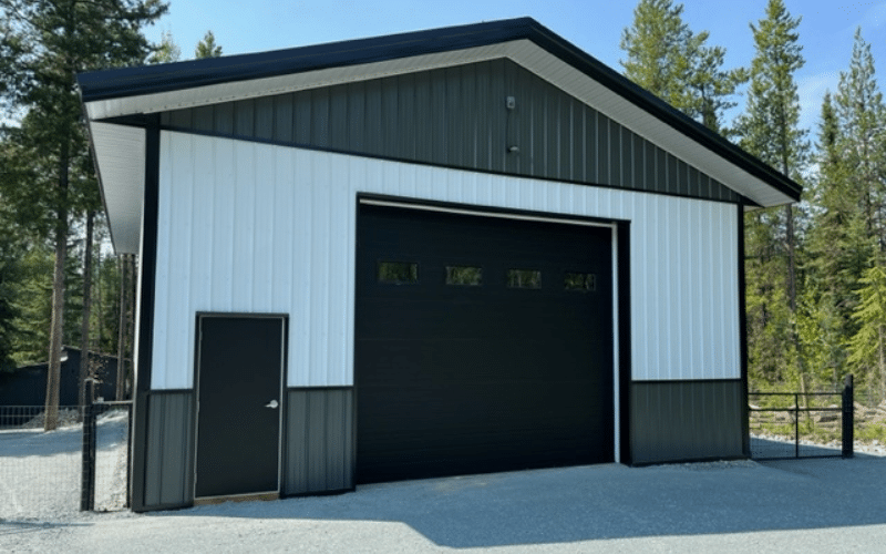 A bright white agricultural post-frame shop with one overhead door and gunmetal wainscoting