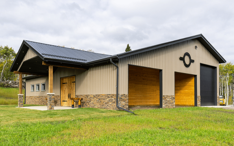 A buckskin post-frame equestrian barn with eight overhead doors