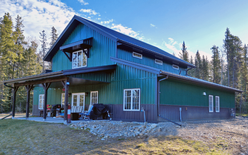A melchers green post-frame residential barndominium with an open lean-to and attached garage