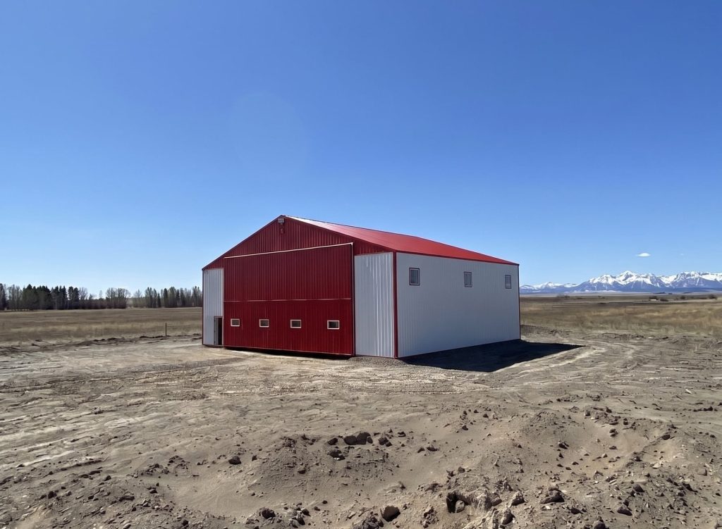A bright white post-frame airplane hangar with a bright red bi-fold door and roof