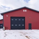 A dark red post-frame agricultural shop