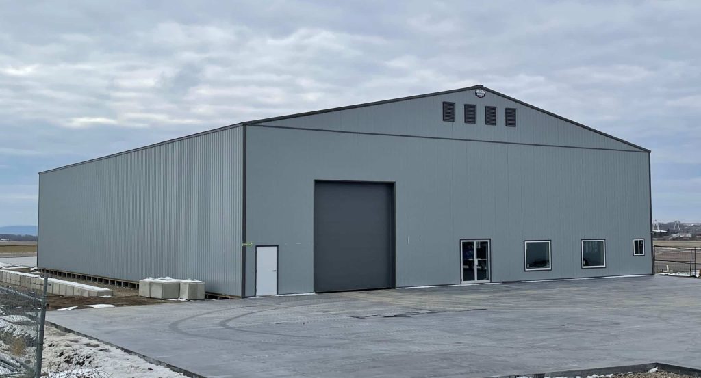 A regent grey post-frame airplane hangar with a bi-fold door