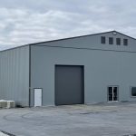 A regent grey post-frame airplane hangar with a bi-fold door