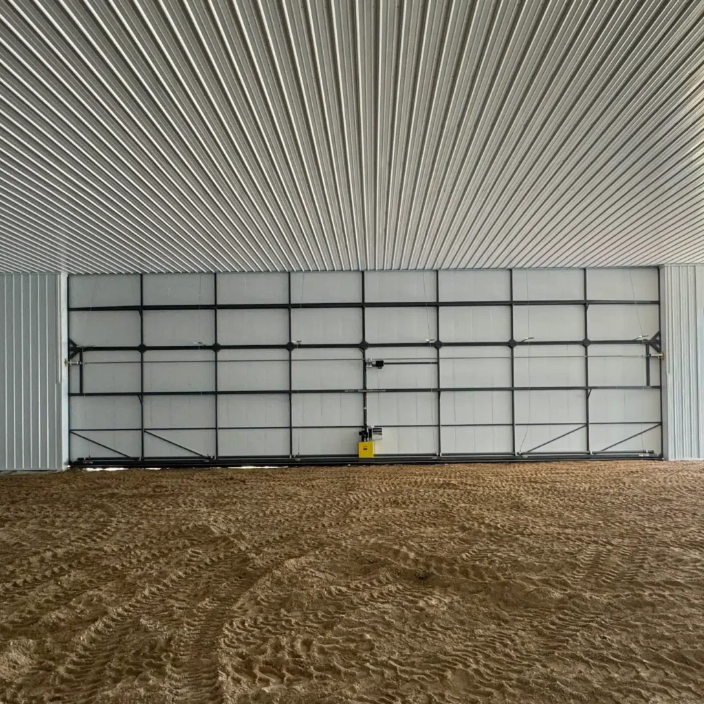 An antique linen post-frame airplane hangar with an overhead and bi-fold door