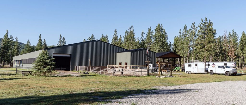 A dark sage post-frame equestrian Riding Arena with overhead doors and skylight