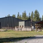 A dark sage post-frame equestrian Riding Arena with overhead doors and skylight