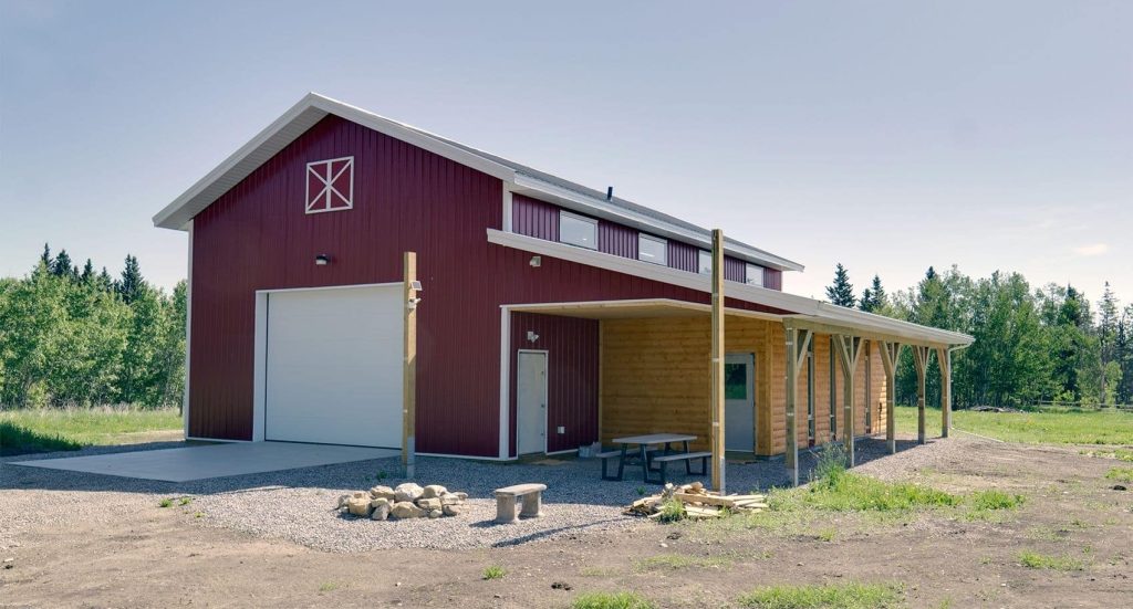 A dark red post-frame equestrian barn