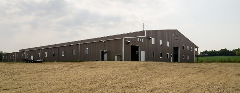 A buckskin post-frame riding arena with two overhead doors