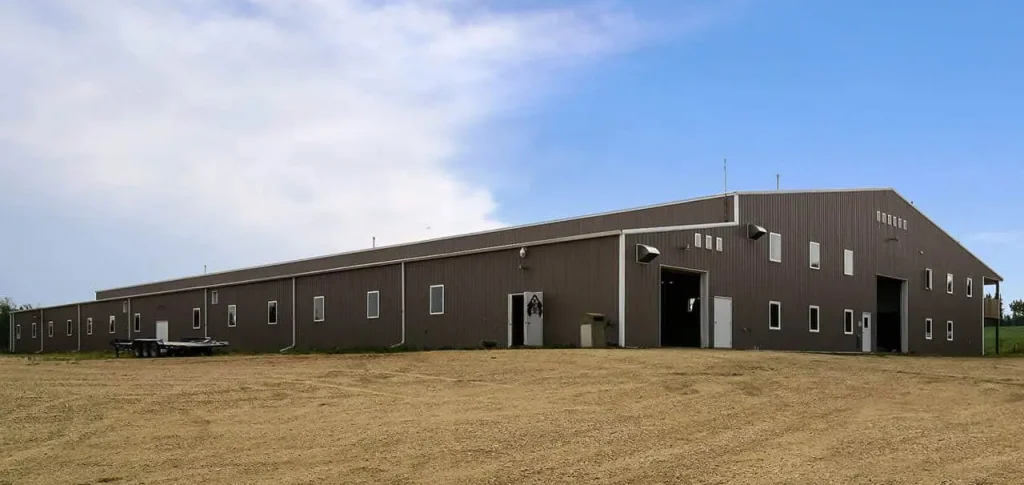 A buckskin post-frame riding arena with two overhead doors