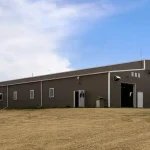 A buckskin post-frame riding arena with two overhead doors