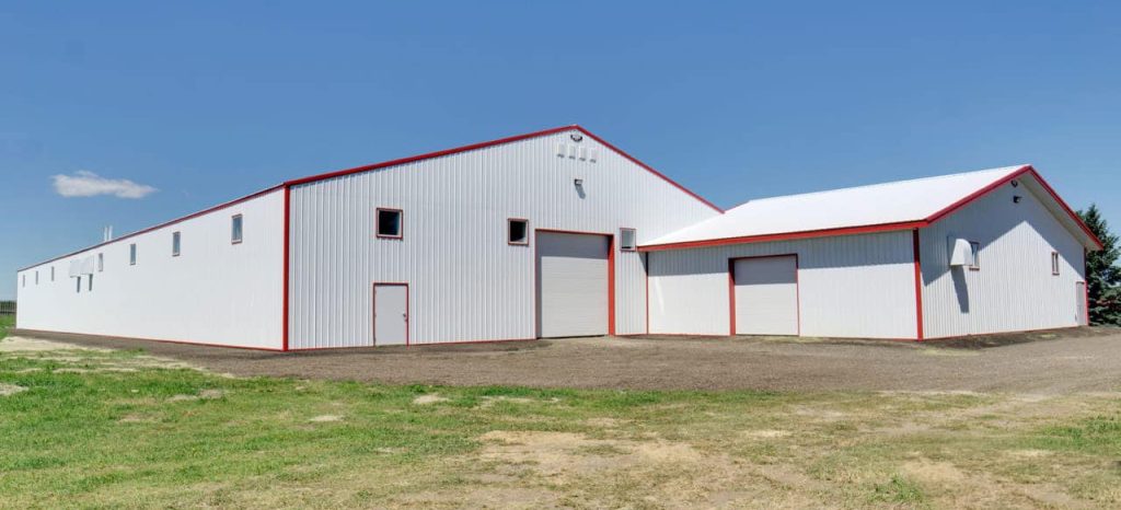 A bright white post-frame riding arena with two overhead doors