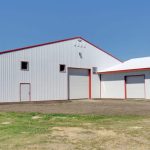 A bright white post-frame riding arena with two overhead doors