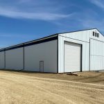 A bright white post-frame agricultural storage building with bi-fold and overhead doors