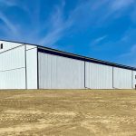 A bright white post-frame agricultural storage building with bi-fold and overhead doors