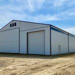 A bright white post-frame agricultural storage building with bi-fold and overhead doors