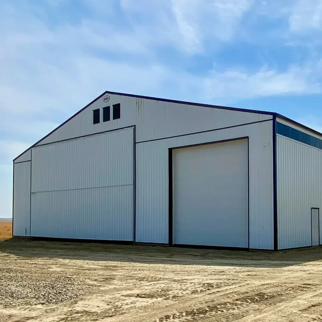 A bright white post-frame agricultural storage building with bi-fold and overhead doors