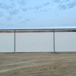 A bright white post-frame agricultural storage building with bi-fold and overhead doors