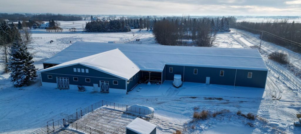 A slate blue post-frame equestrian riding arena