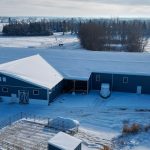 A slate blue post-frame equestrian riding arena