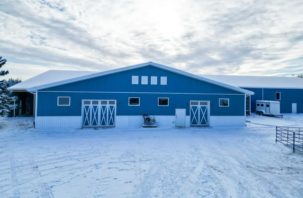 A slate blue post-frame equestrian riding arena