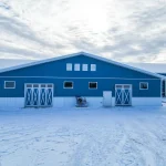 A slate blue post-frame equestrian riding arena