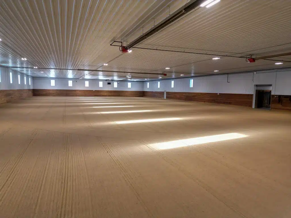 A slate blue post-frame equestrian riding arena