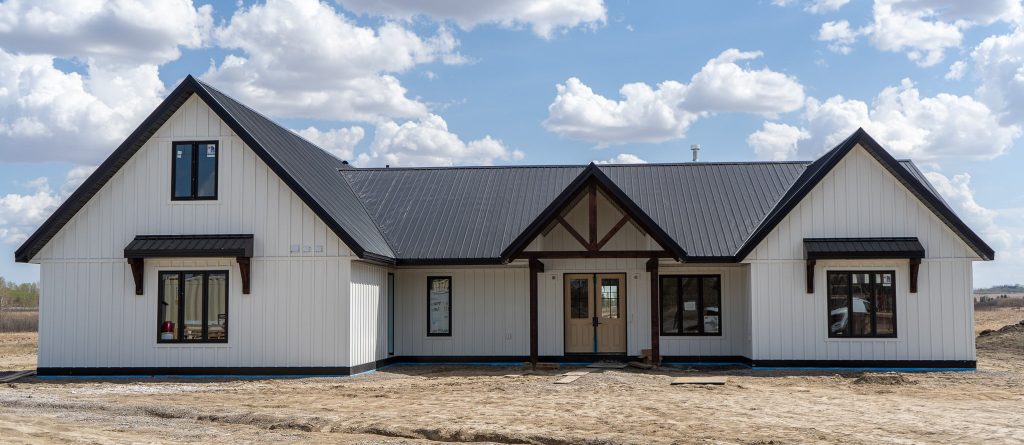 A white white post-frame Homestead with loft, with an overhead door, soffits, and timber accents