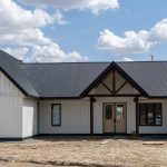 A white white post-frame Homestead with loft, with an overhead door, soffits, and timber accents