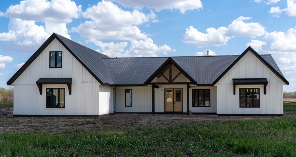 A white white post-frame Homestead with loft, with an overhead door, soffits, and timber accents