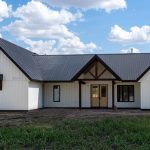 A white white post-frame Homestead with loft, with an overhead door, soffits, and timber accents