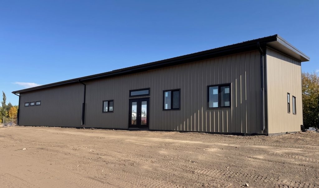 A buckskin post-frame Prairie Peak with soffits, closed lean-tos, and overhead doors