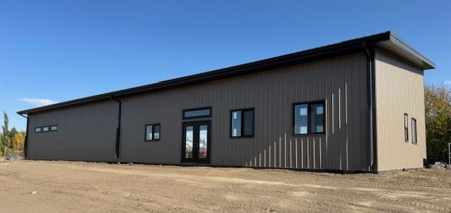 A buckskin post-frame Prairie Peak with soffits, closed lean-tos, and overhead doors
